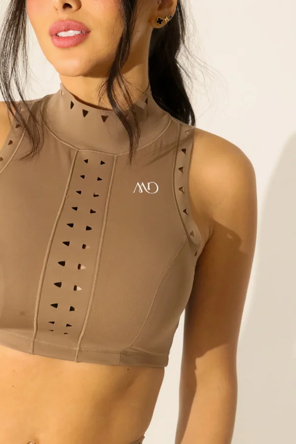 Detalle del top del set Zafiro, conjunto deportivo beige con cuello alto y perforaciones decorativas